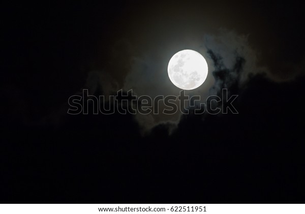 Full moon above cloudy\
sky