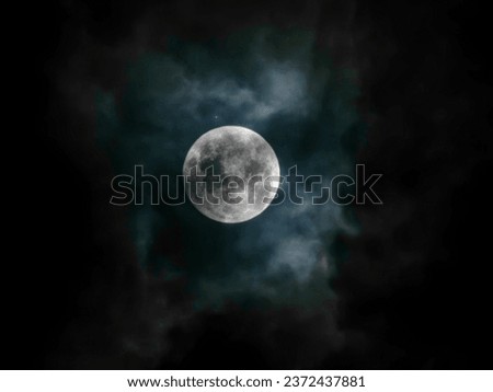 Full Moon in behind clouds on the night sky. Halloween night. All Hallows Eves. Horror sky
