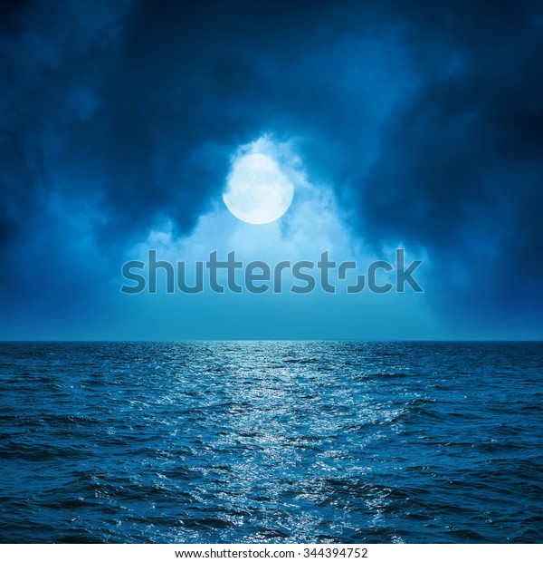 full moon in clouds\
over dark blue sea