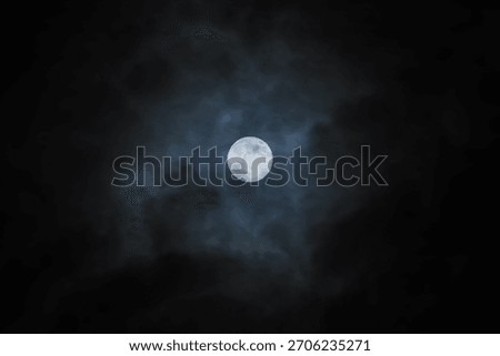 Full moon in a cloudy sky. The moon breaks through the clouds.