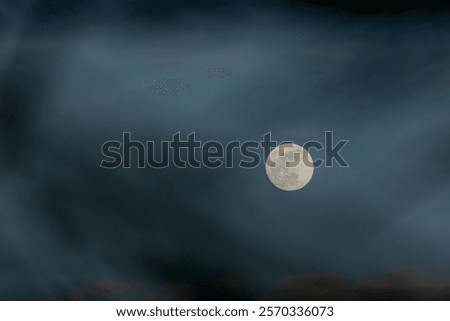 Full moon in the dark sky with dramatic clouds, showcasing the beauty of the night, natural phenomena, and a serene and mysterious atmosphere in the night sky.