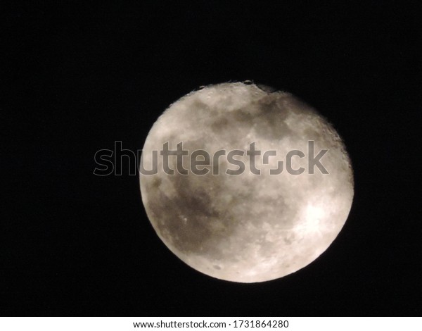 
     the full moon with dark spots on the black sky  
