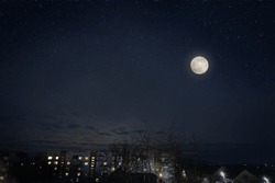 Full Moon In Dark Star Sky Over Town Roofs.