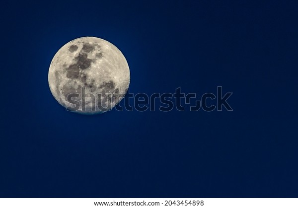 Full moon framed to the left with deep blue\
clear background