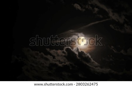 Full Moon Glowing Through Dramatic Clouds in a Dark Night Sky