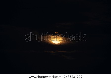 Full Moon Glows Through Thin Cloud Cover against dark sky
