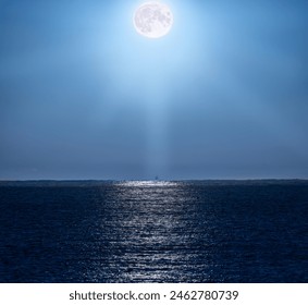 Full moon illuminating the clear, bluish night sky and with its rays of light beautifully reflected in the water of the Mediterranean Sea and illuminating a backlit fishing boat on the horizon line. - Powered by Shutterstock