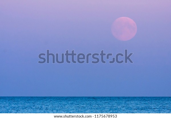 Full moon, a lunar phase, above the sea. Late\
evening up North. Colorful\
sky.