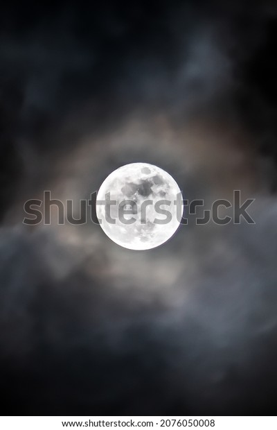 full moon in the\
middle of clouds at night 