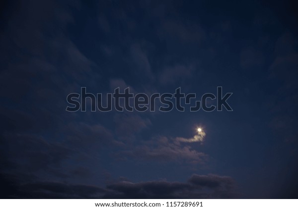 Full\
moon in the middle of warm coloured clouds at\
dusk
