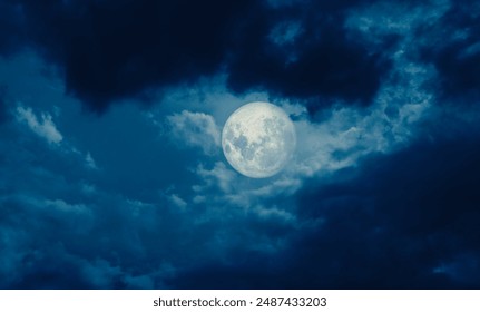 Full moon at midnight and dark blue sky with clouds. Spooky dark night sky view.