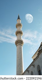 Full Moon And Mosque Minaret In Blue Sky. Bottom Up View Of Minaret.