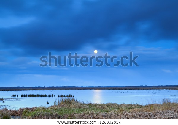 full moon at\
night over lake with long\
exposure