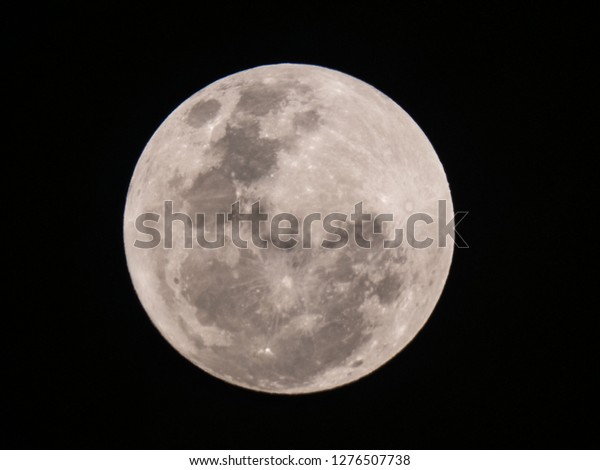 Full moon on dark night sky. The full moon is lunar\
phase when It appears fully illuminated from Earth\'s perspective.\
It occurs when Earth is located between Sun and Moon appears as a\
circular disk