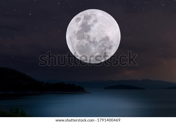 Full moon over lake in the\
night.
