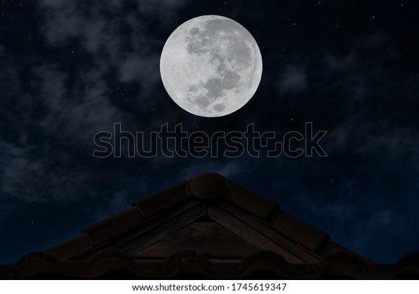 Full moon over roof in the\
night.