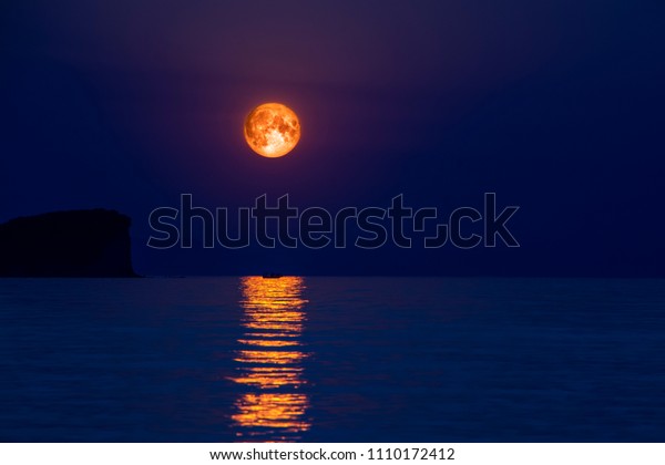 Full moon over the sea with\
abstract shining water and boat silhouette in moonlight\
reflection