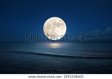 Full moon over the sea with sea wave on sandy beach. (Elements of the moon image furnished by NASA)