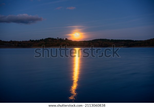 Full moon reflection on a lake at night in\
Sabugal Dam, Portugal