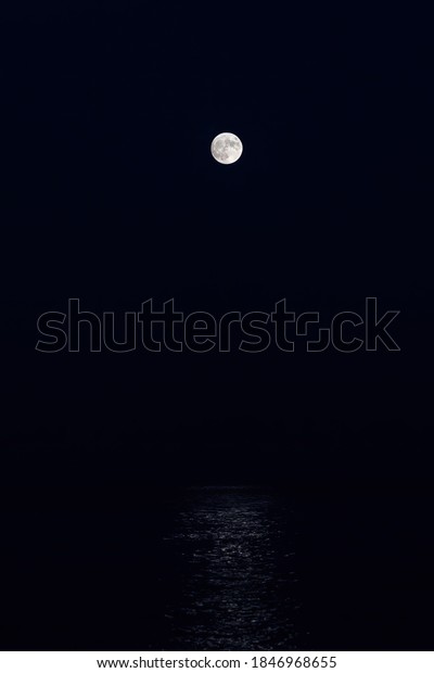 Full moon reflection over the evening sea in\
Spanish Costa Brava