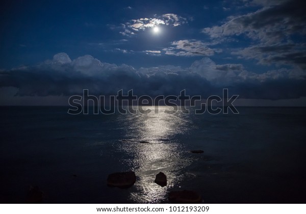 Full moon\
and reflection in sea, beautiful\
clouds.