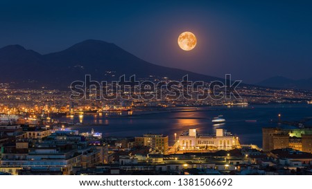 Full moon rises above Mount Vesuvius, Naples and Bay of Naples, Italy. Moonlight reflected in calm sea. Elements of this image furnished by NASA.