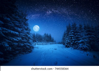 Full moon rising above the winter forest covered with fresh snow. Fantastic bright milky way in a starry sky. Christmas night.