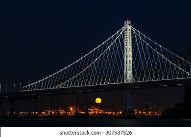 The Full Moon Rising Behind The New Oakland Bay Bridge At Night.