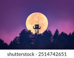 Full moon setting over fire tower in Palencia, in blue hour