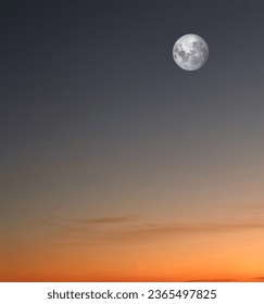 Full moon shining in cloudless sky at sunset