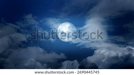 Full moon shining in the cloudy sky at midnight. Eerie, dark night skyscape.Dark blue sky, moon and clouds.
