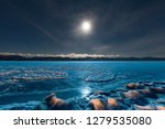 Full moon shining over blue ice surface of frozen Lake Laberge, Yukon Territory, Canada