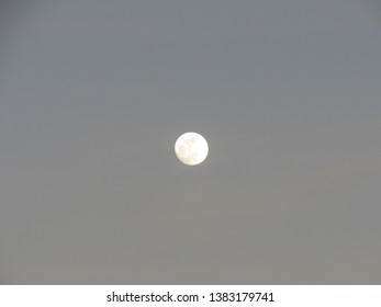 A full moon in the sky rising before sunset 