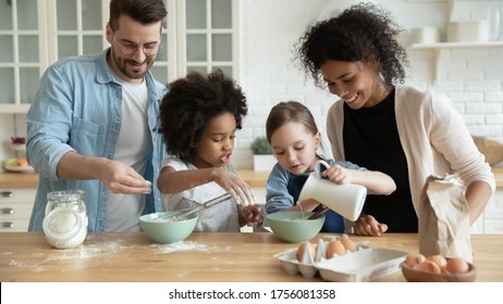 Full multi ethnic family with adorable daughters gathered in modern kitchen cooking pancakes together. Cake mix preparation, make yummy home-made dessert, enjoy communication and cookery hobby concept