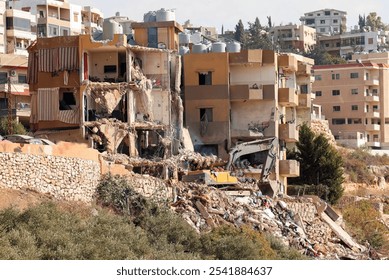 Full outdoor shot of a heavily damaged multi-story apartment building complex. The foreground shows a large pile of rubble and debris from the demolition - Powered by Shutterstock