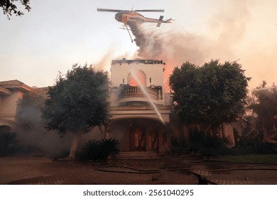 Full outdoor shot of a large house engulfed in flames, with firefighters actively battling the intense blaze. - Powered by Shutterstock