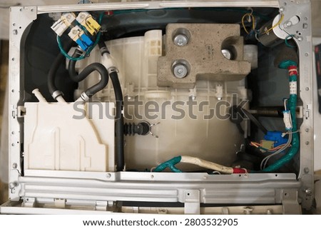 Full overhead view of completely disassembled washing machine interior showing drum tank motor counterweight hoses and colorful wiring system
