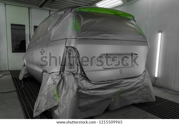 Full painting of a silver car in the back of a\
hatchback, some parts of which are protected by paper from splashes\
of paint droplets in a car body repair shop with a special box and\
equipment