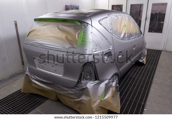 Full painting of a silver car in the back of a\
hatchback, some parts of which are protected by paper from splashes\
of paint droplets in a car body repair shop with a special box and\
equipment