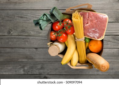 Full Paper Bag Of Groceries On Wooden Background With Copy Space, Top View