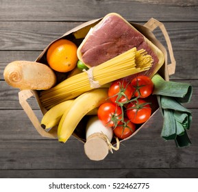 Full Paper Bag Of Various Groceries On Wooden Background, Top View