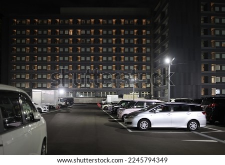 Full parking lot by multi-story hotel building at night