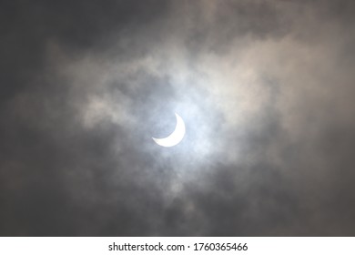 Full and partial Solar Eclipse seen in the cloudy sky.