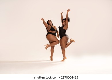 Full Photo Of Superb Plus Size Dark Skinned Two Women In Black Fashionable Swimwears, Laughing And Dancing, Having Fun Together. Concept Of Body Acceptance, Body Positivity And Diversity. 