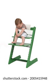 Full Portrait Of A Baby Sitting In A Highchair Look Down On White Background