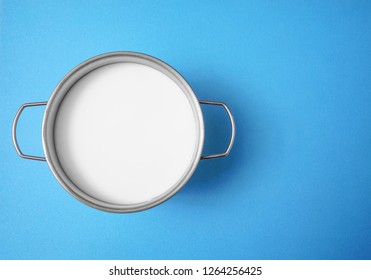 Full Pot Of White Milk. Top View. Isolated On Blue  Background. Metal Saucepan. 