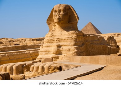 The full profile including head, feet and entire body of the Great Sphinx with the pyramid of Menkaure in the background in Giza, Egypt with nobody in frame. Horizontal copy space