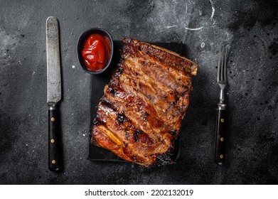 Full Rack Of BBQ Grilled Pork Spare Ribs On A Marble Board. Black Background. Top View.