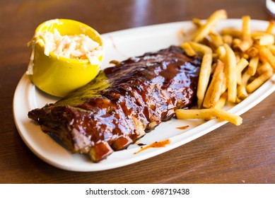 Full Rack Of Ribs BBQ On White Plate With French Fries And Salad