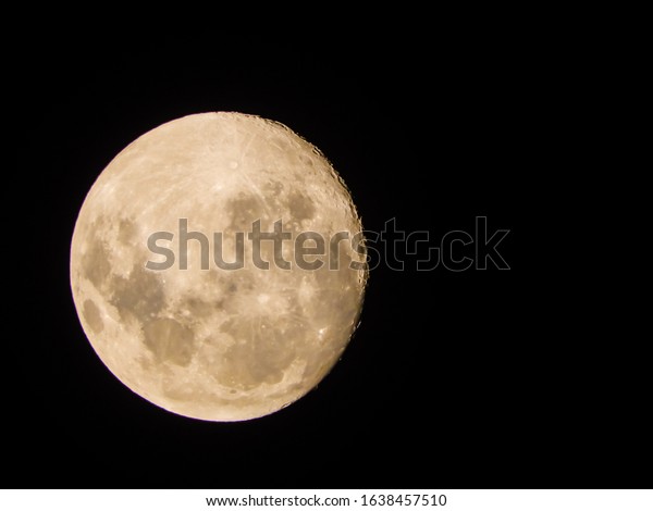 A full red super moon with\
detailed surface isolated on the sky with copy space on the\
right.